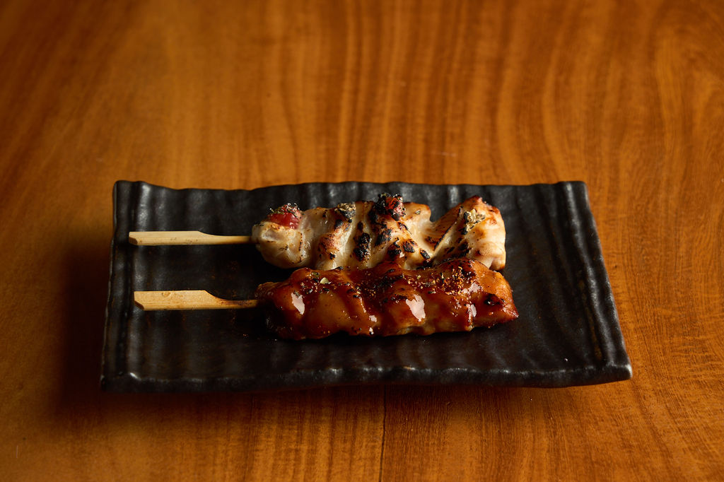 Anaba yakitori — glazed chicken skewers on a black ceramic plate